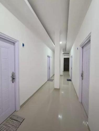 un pasillo vacío con paredes blancas y puertas blancas en Highlander Stay Palembang en Palembang