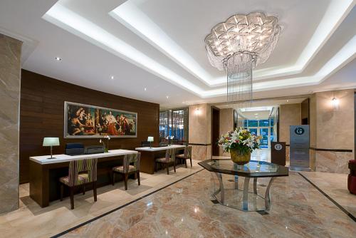 a lobby with a chandelier and tables and chairs at The George Hotel in Lagos
