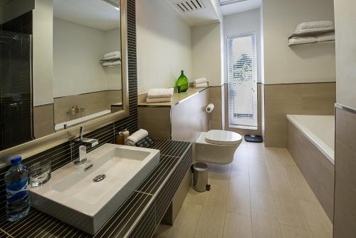uma casa de banho com um lavatório, um WC e uma banheira em The George Hotel em Lagos