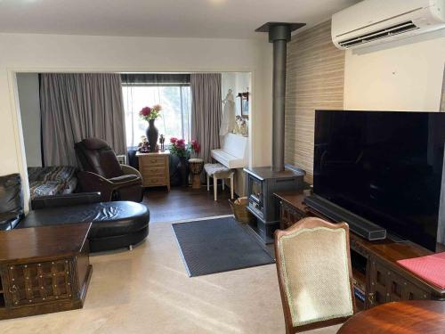 a living room with a flat screen tv and a living room with a fireplace at Jindaburra Cottage in Jindabyne