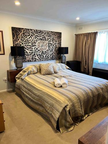 a bedroom with a large bed with two towels on it at Jindaburra Cottage in Jindabyne