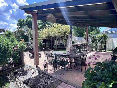 a patio with a table and chairs under a pavilion at Jindaburra Cottage in Jindabyne