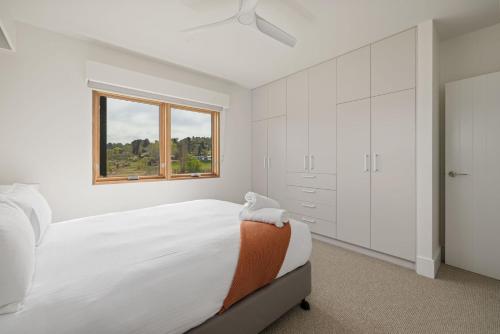 een witte slaapkamer met een bed en een raam bij Kosci Lakeside B in Jindabyne