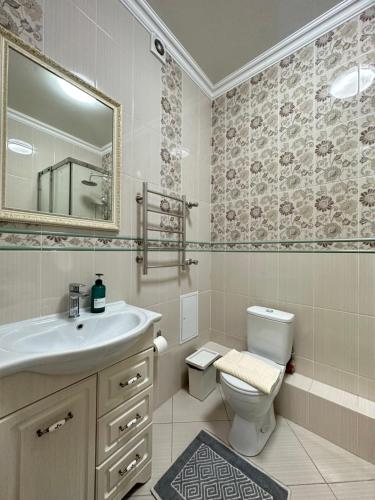 uma casa de banho com um lavatório, um WC e um espelho. em Однокомнатные апартаменты на Экспо em Taldykolʼ