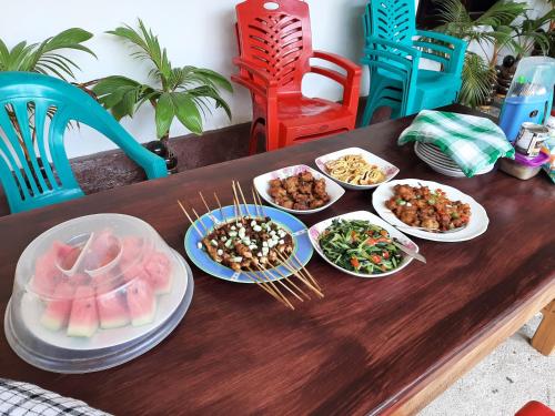 una mesa de madera con platos de comida. en Riung Tiga Empat Tujuh Guesthouse, en Riung