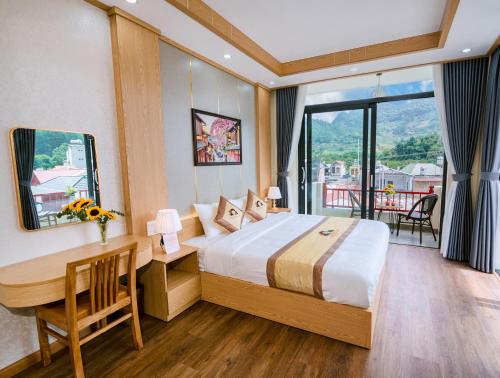 a hotel room with a bed and a desk and a window at Khách sạn Kumo Chan Mộc Châu in Mộc Châu