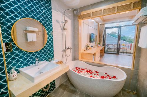 ein Badezimmer mit einer Badewanne, einem Waschbecken und einem Spiegel in der Unterkunft Khách sạn Kumo Chan Mộc Châu in Mộc Châu