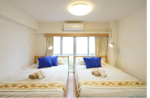 two beds in a room with blue pillows at 【Shinjuku33】光回線完備パーティースペースにも使える新宿のお部屋 in Tokyo
