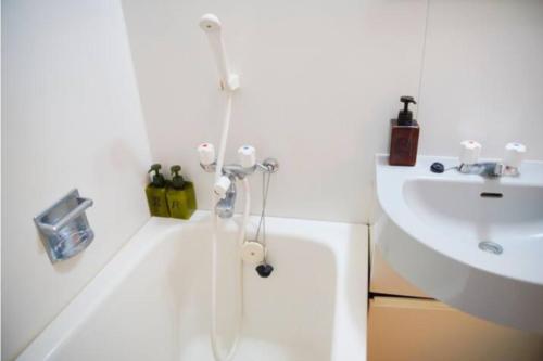 La salle de bains blanche est pourvue d'un lavabo et d'une douche. dans l'établissement 【Shinjuku33】光回線完備パーティースペースにも使える新宿のお部屋, à Tokyo