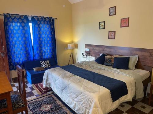 ein Schlafzimmer mit einem großen Bett und blauen Vorhängen in der Unterkunft Viva Villa in Jhājra