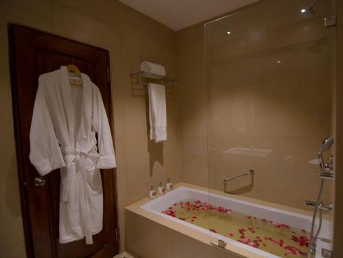a bathroom with a tub and a robe on the wall at Norkhil Boutique Hotel & Spa in Thimphu