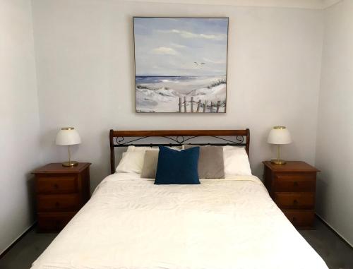 a bedroom with a bed with two lamps and a painting at SHELLHARBOUR BEACH COTTAGE ---- Back gate onto Beach, Front gate walk to Marina in Shellharbour