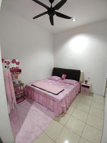 a bedroom with a pink bed and a ceiling fan at Wan K Homestay Gua Musang in Gua Musang
