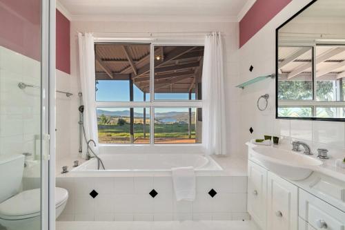a white bathroom with a tub and a sink and a window at Mountain Lowry Lodge in Jindabyne