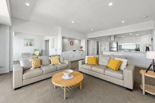 a living room with two couches and a table at Proximity Waterfront Apartments in Redcliffe