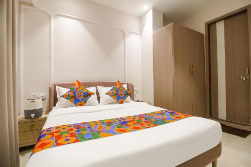 a bedroom with a large white bed with colorful pillows at FabHotel Sharma & Vishnu Garden in Bhopal