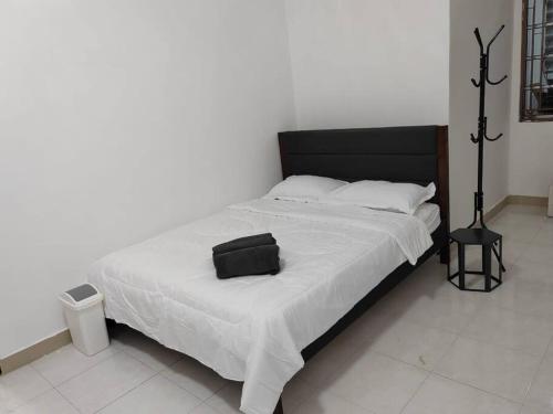 a large bed with a black headboard and white sheets at D'Sroja Home in Jerantut in Jerantut