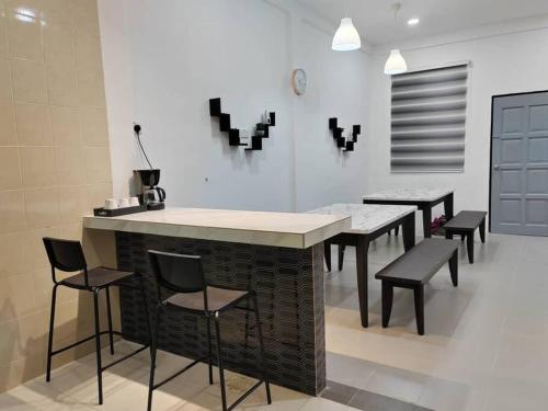a kitchen with a counter with chairs and tables at D'Sroja Home in Jerantut in Jerantut