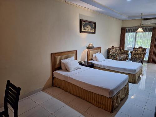 Pokój hotelowy z 2 łóżkami i krzesłem w obiekcie Makati Pasuruan Hotel w mieście Pasuruan