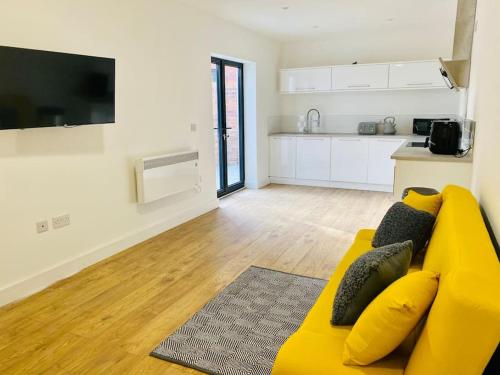 a living room with a yellow couch and a kitchen at Ten - Central Apartment - Contractors Professionals in Gloucester