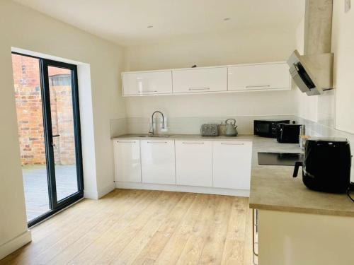 a kitchen with white cabinets and a wooden floor at Ten - Central Apartment - Contractors Professionals in Gloucester