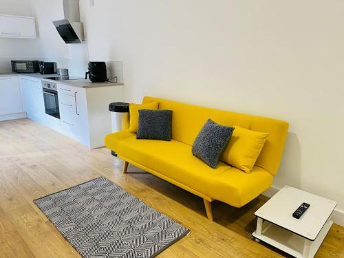 a yellow couch in a living room with a kitchen at Ten - Central Apartment - Contractors Professionals in Gloucester