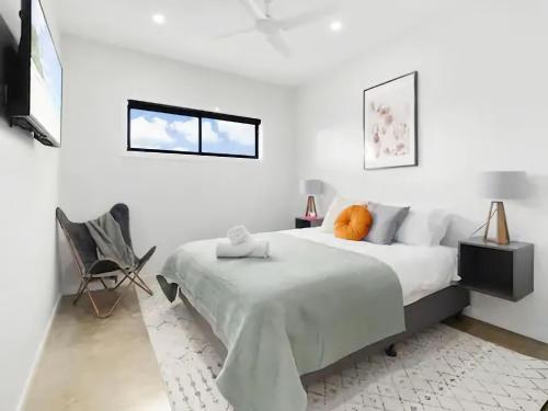 a white bedroom with a bed and a chair at Billy Button Retreat in Kalkite