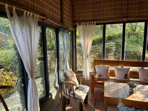a room with large windows and a chair and a table at H’nee House Ta Van in Sa Pa