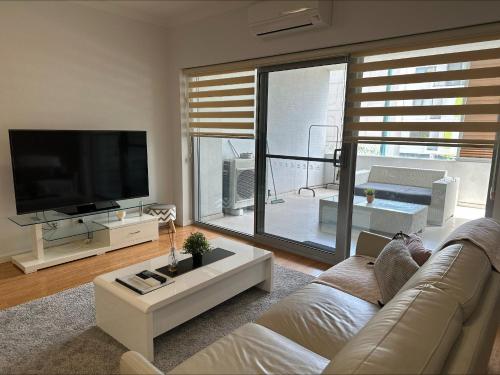 a living room with a couch and a tv at 2 On Trend Condo Near Crown 1br in Perth