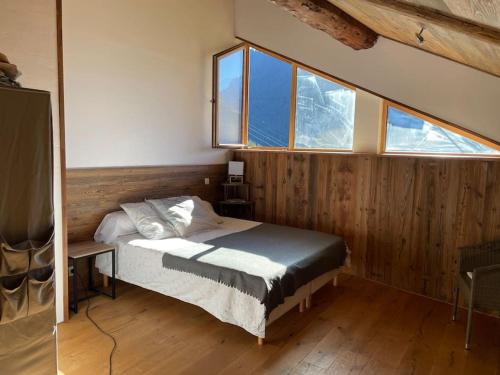 a bedroom with a bed in a room with windows at Chalet au cœur de la haute Tarentaise in Séez