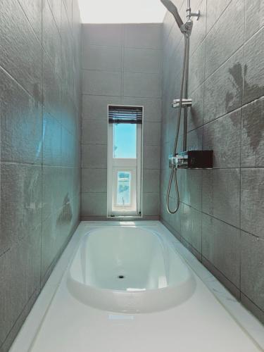 a bath tub in a bathroom with a window at MO Guesthouse in Jeju