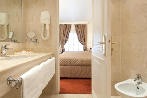 baño con lavabo y cama en Grand Hôtel Moderne en Lourdes