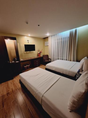 a hotel room with two beds and a flat screen tv at Alunsina Hotel and Spa in Roxas City