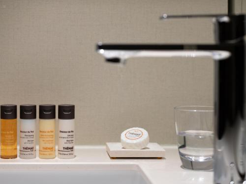 a bathroom counter with three bottles and a glass of water at Hotel The Celestine Kyoto Gion in Kyoto