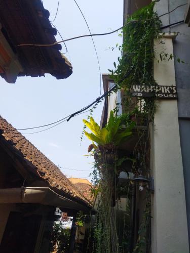 a street sign on a building with plants at Wahwik's House in Ubud