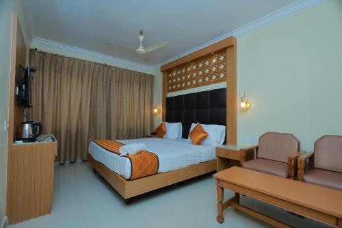 a hotel room with a bed and a chair at Hotel Sangam in Kanyakumari