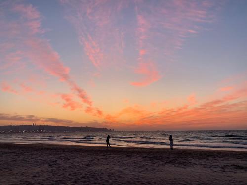 dos personas de pie en la playa al atardecer en אירוח סמוך לים התיכון, en Haifa