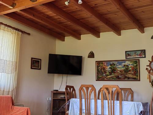 a dining room with a table and a flat screen tv at Plataniotissa Mansion in Kalavrita