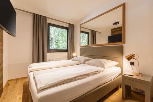 a bedroom with two beds and a mirror at Saalbach Suites by ALPS RESORTS in Saalbach-Hinterglemm