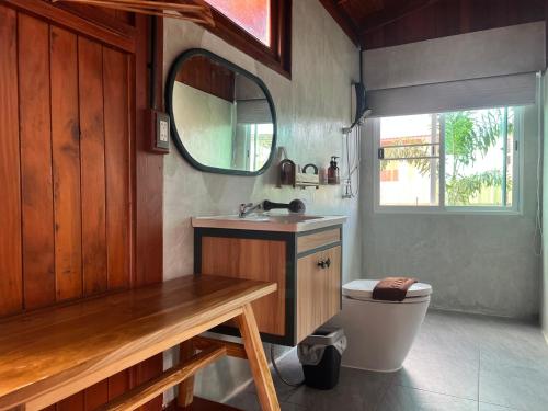 a bathroom with a sink and a toilet and a mirror at Bann Rai I Na in Phrae