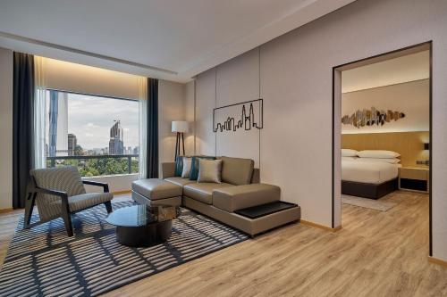 a living room with a couch and a bed and a mirror at Renaissance Kuala Lumpur Hotel & Convention Centre in Kuala Lumpur