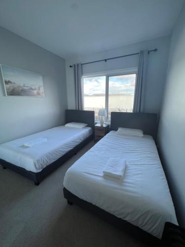 twee bedden in een kamer met een raam bij Howrah Getaway (Entire Place, Private Entrance, Breakfast included) in Howrah