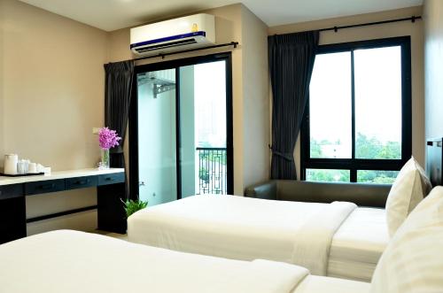 Bangkok NoiにあるNORN Rimkhlong Bangkok นอนริมคลองのベッド2台と窓が備わるホテルルームです。