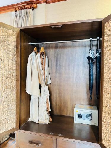 a room with a closet with a microwave and umbrellas at Yotaka Boutique Hotel Bangkok in Bangkok