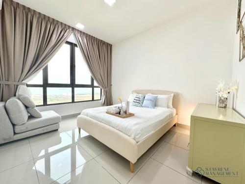 a bedroom with a bed and a couch and a window at Bali Residences Sea View Suites Melaka in Melaka