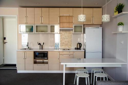a kitchen with a refrigerator and a table and stools at Tumar Apart Hotel in Karagandy