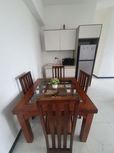 a kitchen with a wooden table and chairs and a kitchen with a refrigerator at Blue Ocean in Dehiwala
