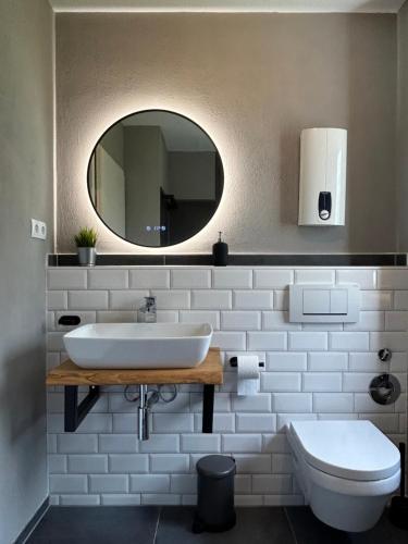 een badkamer met een wastafel, een toilet en een spiegel bij Ferienwohnung Meeresbucht in Sassnitz
