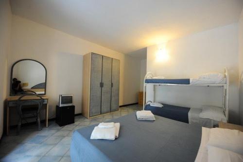 a bedroom with two beds and a desk and a mirror at Villaggio La Marée in Pisciotta