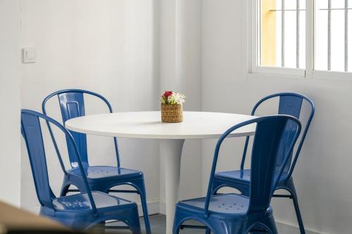 a white table with four blue chairs and a vase on it at Brisa del mar in Chilches